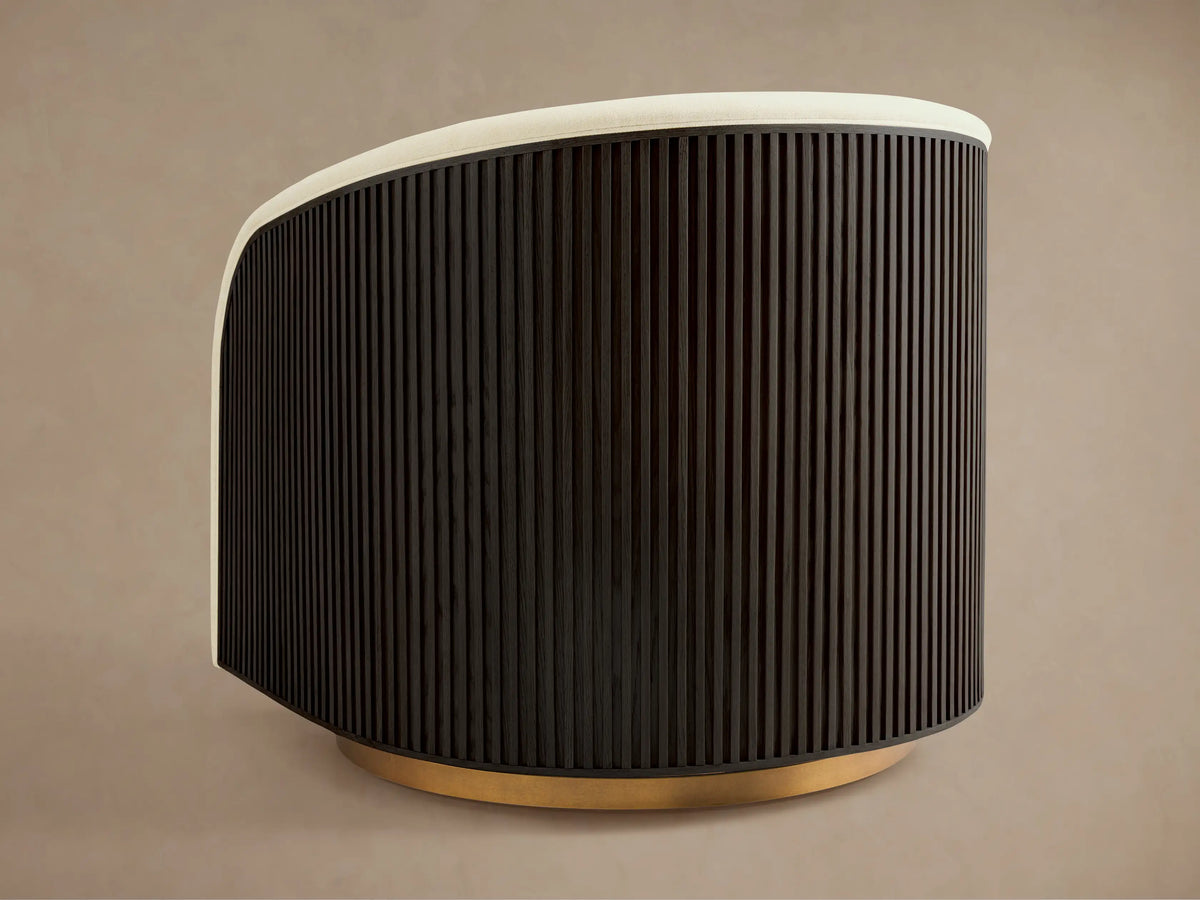 Finnley Swivel Chair side view, dark ribbed wooden back, light cushioned upholstery, gold swivel base on neutral background.