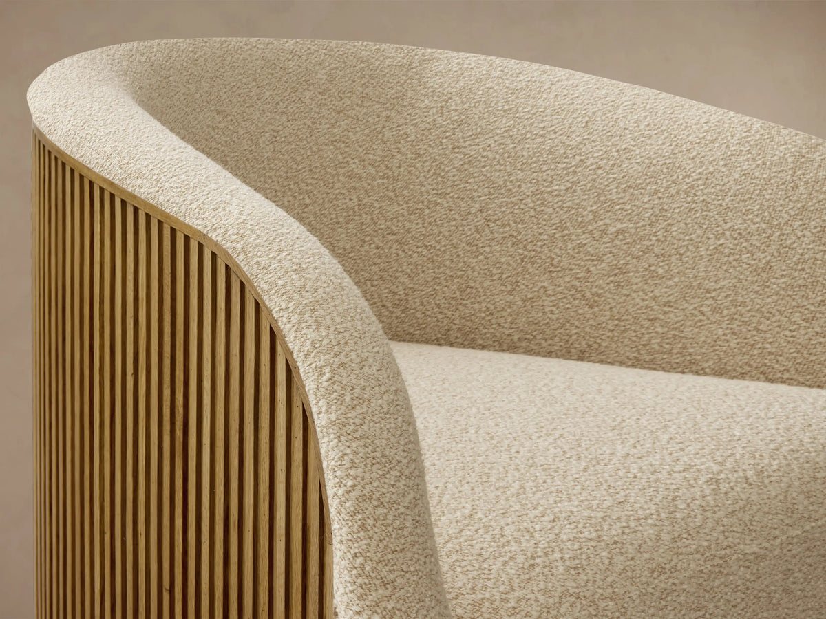 Close-up of the light beige textured upholstery on the Finnley Swivel Chair, showing its curved back and side with honey-finished white oak vertical slats.