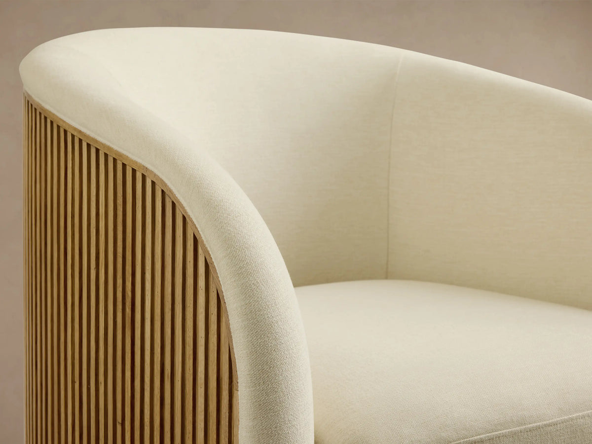 Finnley Swivel Chair in cream fabric with round, cushioned seat and backrest, set on a wooden floor.