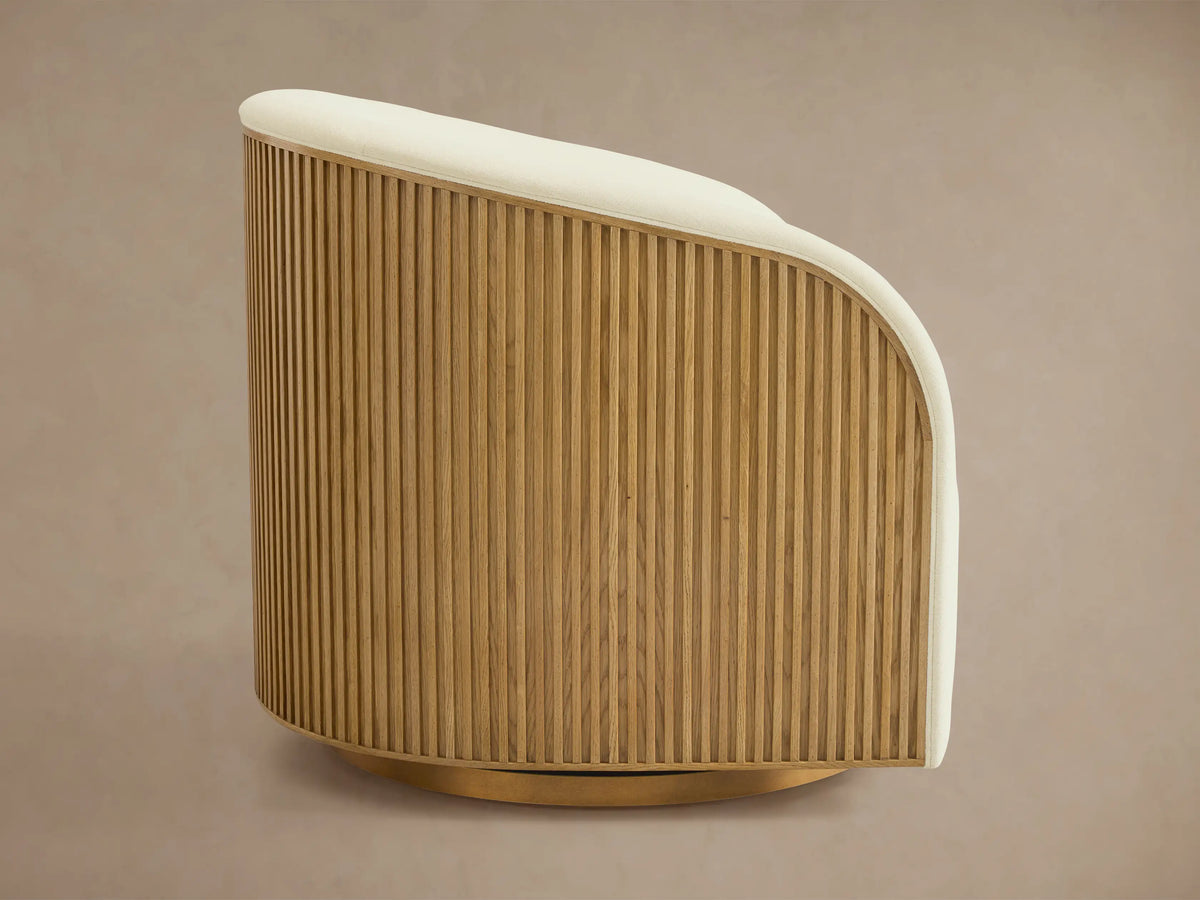 Finnley Swivel Chair featuring curved cream fabric upholstery, vertical wood slat back, and soft cushioning against a neutral background.