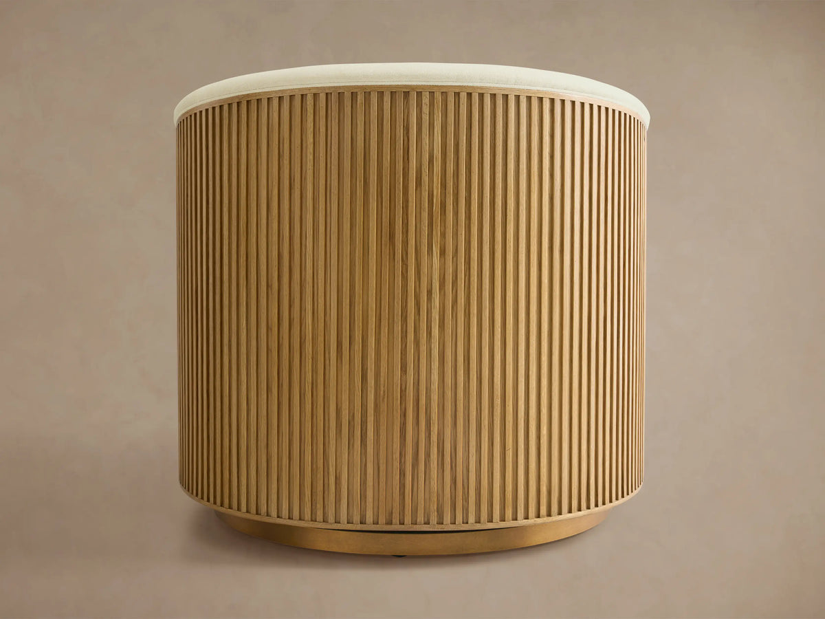 Finnley Swivel Chair with a curved back, featuring vertical wooden slats in a honey finish. Beige cushion edges peek at the top.