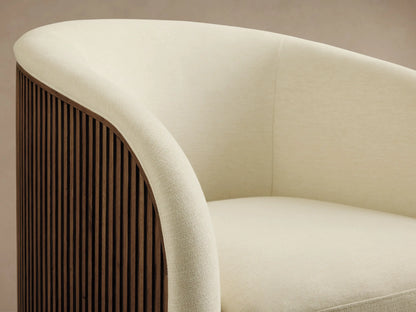 Finnley Swivel Chair in cream fabric, with rounded backrest and seat, on a wooden floor, featuring a gold-toned swivel base.
