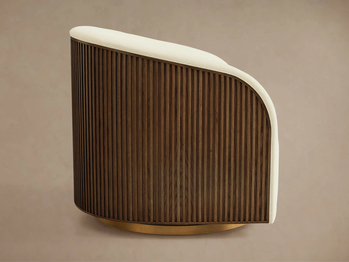 Finnley Swivel Chair with a creamy upholstered seat and backrest, featuring a curved design. The side showcases vertical wooden slats in a dark finish.