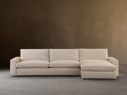 Kipton Wide Arm Two-Piece Chaise Sectional in a beige fabric. It features wide arms, a chaise on the left, and plush cushions on a wooden floor.