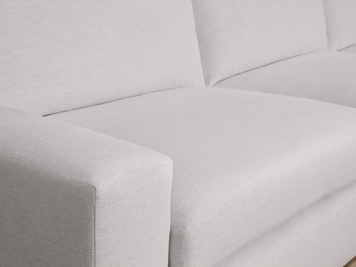 Kipton sectional close-up showing a light gray fabric with wide armrests, plush seat and back cushions, illustrating its soft texture.