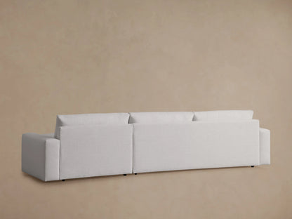 Back view of the Kipton Wide Arm Two-Piece Chaise Sectional in neutral fabric, showing wide arms and plush cushions against a beige background.