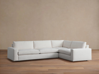 Kipton Wide Arm Two-Piece Sectional in light beige fabric, featuring wide armrests and plush cushions, set on wooden floor.