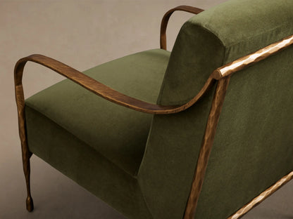 Close-up of the olive green Gwen Chair, showing the velvet upholstery and hammered brass-finished armrests.
