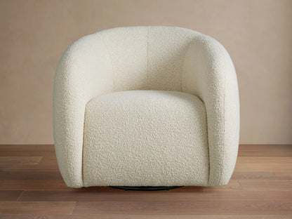 Front view of the cream bouclé-like Fresno Swivel Chair with rounded arms and a plush seat, in a luxurious living room.