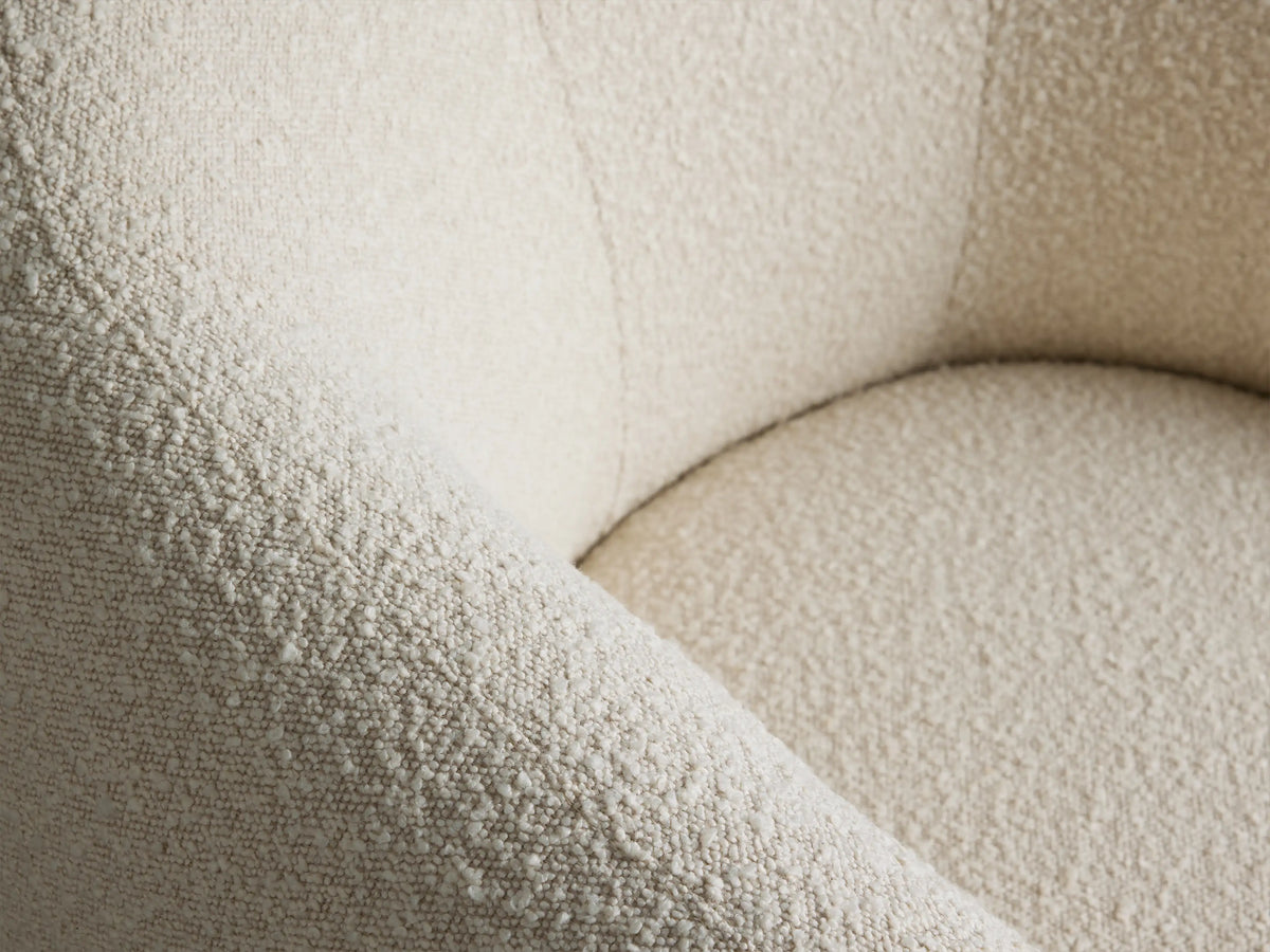 Creamy white boucle Fresno Swivel Chair with curved arms and back, on a black swivel base, against a neutral wall.