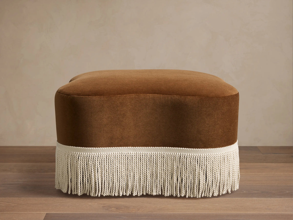 Front view of the brown Barbey Ottoman with Fringe, showing cream fringe along the bottom.