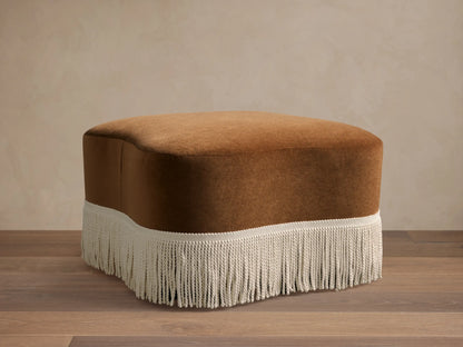 Front view of the brown Barbey Ottoman with Fringe, showing cream fringe along the bottom.