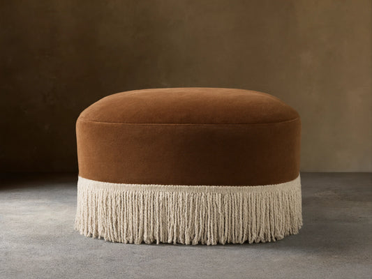 Front view of the brown Barbey Ottoman with Fringe, showing cream fringe along the bottom.