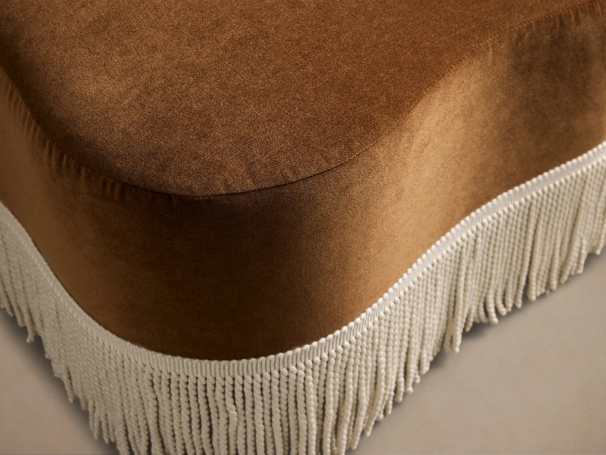 Front view of the brown Barbey Ottoman with Fringe, featuring cream tassel fringe along the bottom edge.