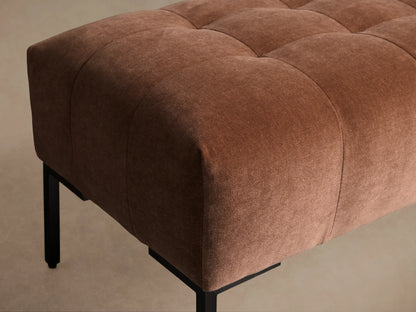 Tilton Tufted Bench, muted terracotta-colored upholstered bench with deep tufting & sleek black metal legs, on a wood floor.