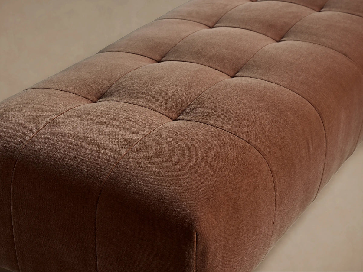 Long, rectangular Tilton Tufted Bench upholstered in a rust-colored fabric with deep square tufting, on black metal legs.