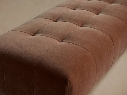 Long, rectangular Tilton Tufted Bench upholstered in a rust-colored fabric with deep square tufting, on black metal legs.