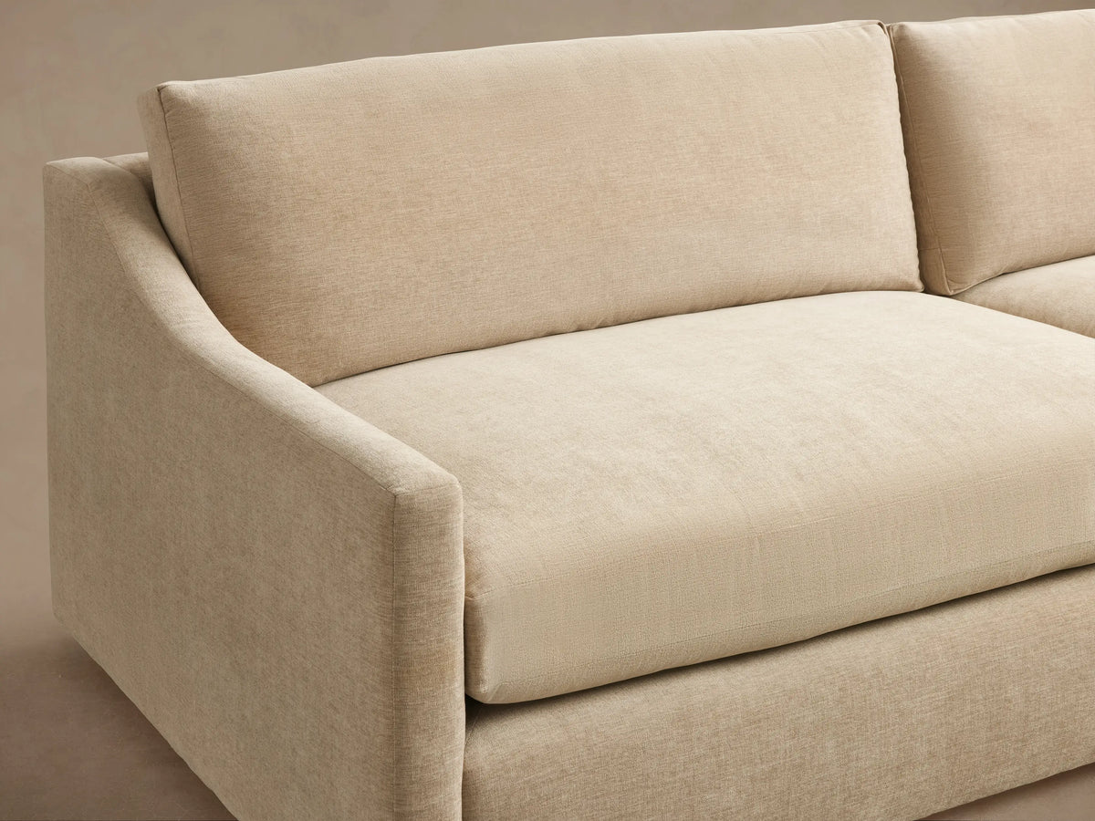 Kipton Slope Arm Sofa in light beige fabric, with two seat and back cushions, and sloped arms, on a wood floor.