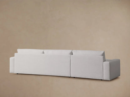 Close-up of the Kipton Wide Arm Two-Piece Chaise Sectional, featuring a light beige fabric, wide armrest, and plush seat cushion.