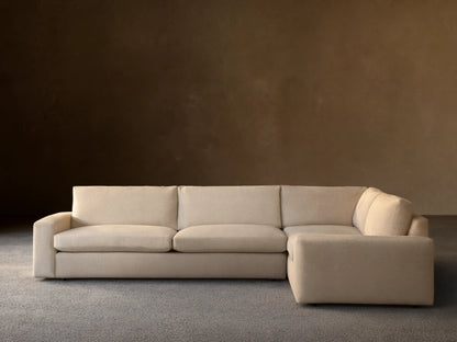 Kipton Wide Arm Two-Piece Sectional in light beige fabric on a wooden floor, with wide arms and plush cushions against a neutral wall.