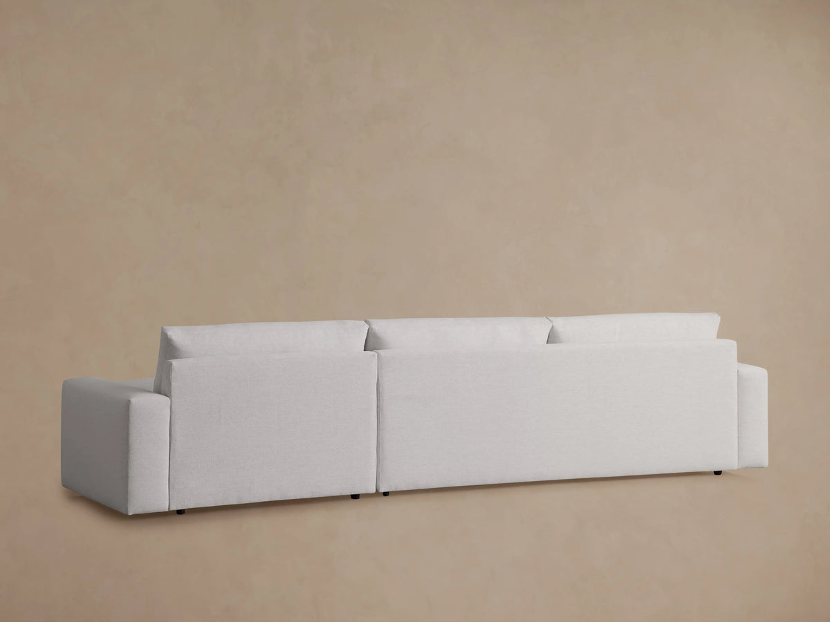 Close-up of the Kipton Wide Arm Two-Piece Chaise Sectional in light fabric, showing wide armrest and plush seat cushion.