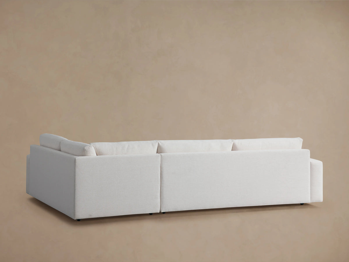 Wide arm two-piece sectional made of light fabric. Features a thick seat cushion, straight wide arm, and padded backrest.