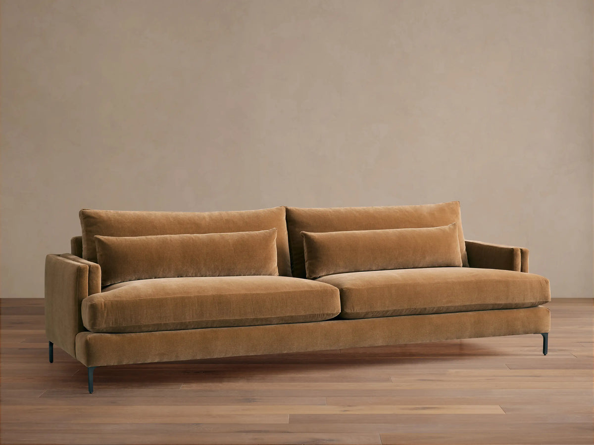 Sumner Sofa: Large, camel-colored velvet sofa with two seat cushions, two back cushions, and two lumbar pillows, on a wood floor.
