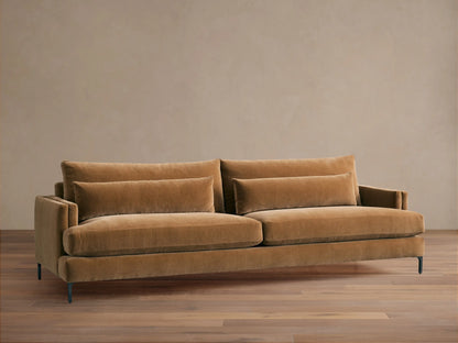 Sumner Sofa: Large, camel-colored velvet sofa with two seat cushions, two back cushions, and two lumbar pillows, on a wood floor.