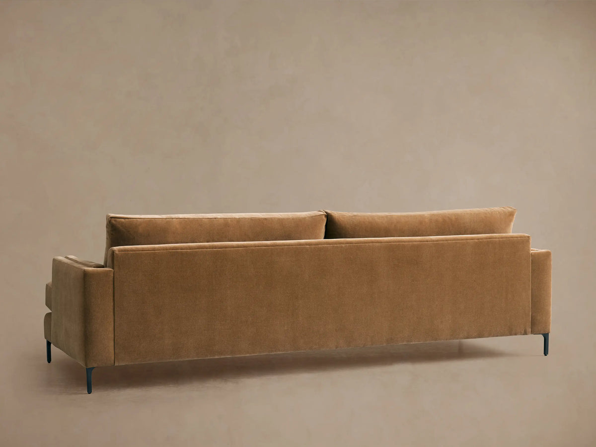 Angled close-up of a plush, warm brown Sumner Sofa armrest, seat, and deep back cushions with a small lumbar pillow.