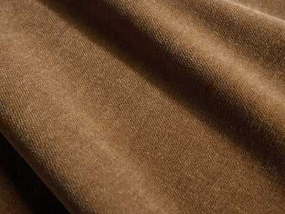 Sumner Sofa, angled rear view, warm caramel velvet fabric, three back cushions, slender dark metal legs against a beige wall.