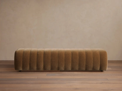 Fresno Channel-Stitched Bench. Long, rectangular, golden-brown upholstered bench with vertical channels, on a wooden floor.