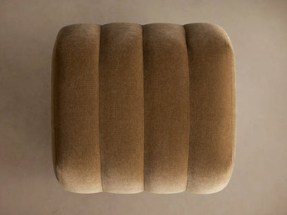 Fresno Channel-Stitched Ottoman, a plush warm brown velvet ottoman with distinct vertical channels and rounded ends.