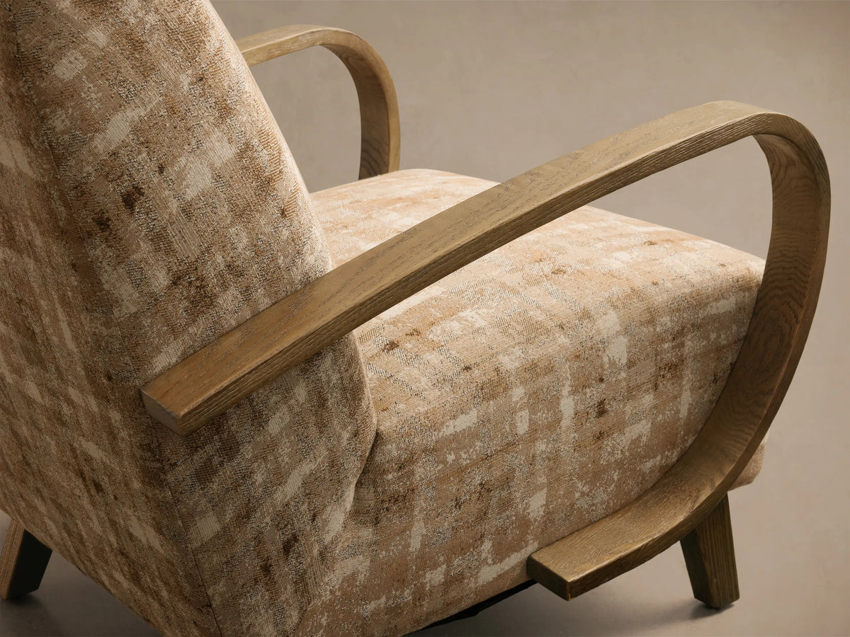 Front view of the Gabel Chair with distressed beige and brown plaid upholstery and curved light wood armrests.