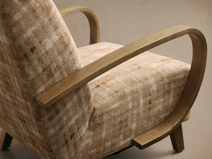 Front view of the Gabel Chair with distressed beige and brown plaid upholstery and curved light wood armrests.