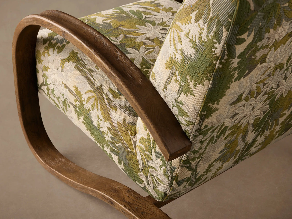 Allora Chair with a green, white & cream foliage upholstered seat/back, framed by curved dark mocha wood arms.