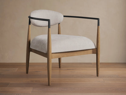 Jagger Chair in Natural with light beige cushioned seat and backrest, wooden legs, and a sleek, black metal frame.