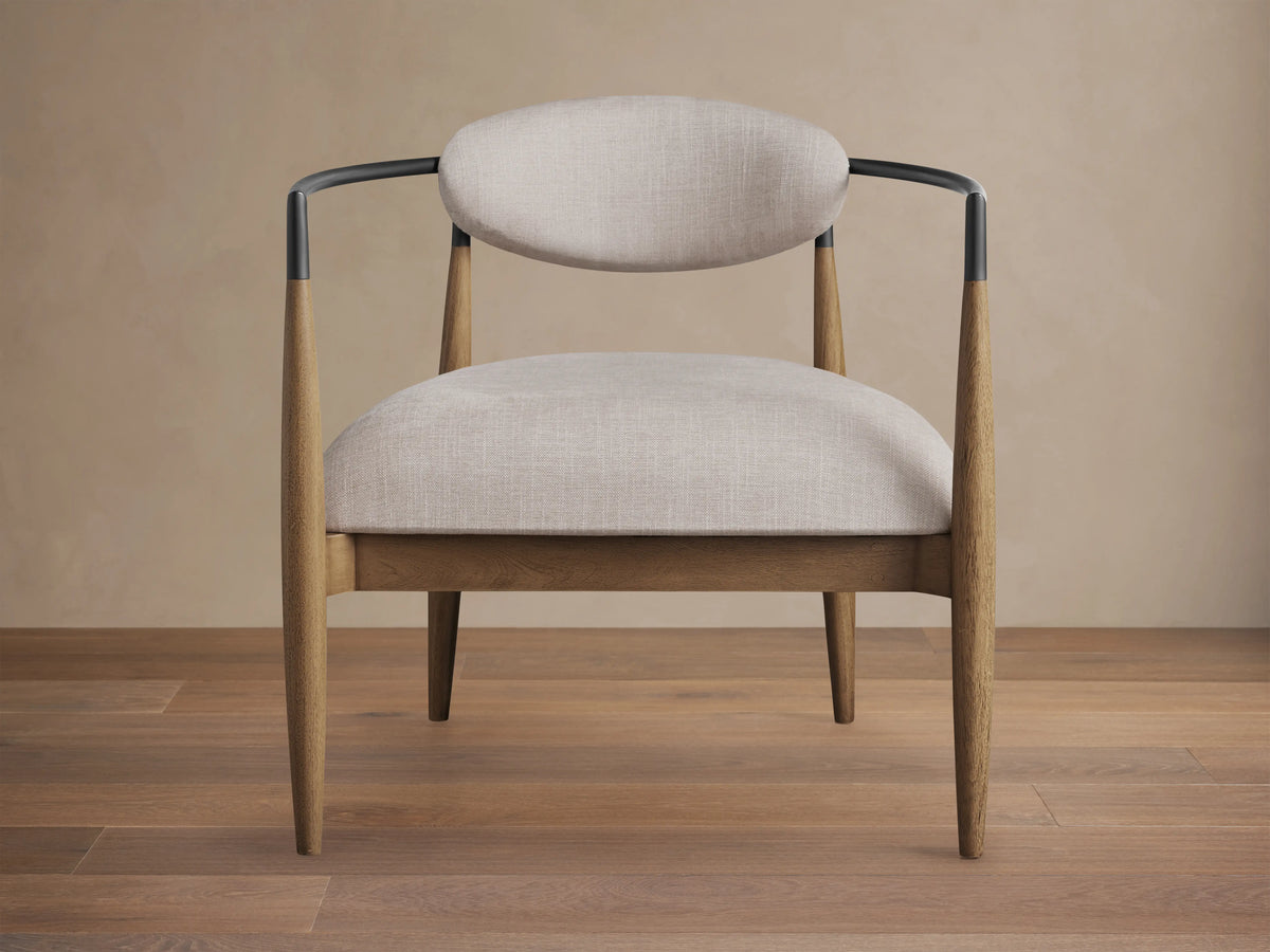 Jagger Chair in Natural with light beige cushioned seat and backrest, wooden legs, and a sleek, black metal frame.