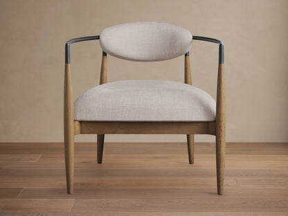 Jagger Chair in Natural with light beige cushioned seat and backrest, wooden legs, and a sleek, black metal frame.