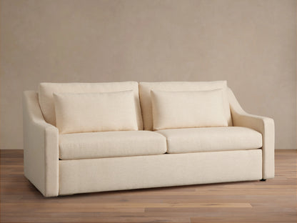Ashby Luxury Sleeper Sofa in a light cream fabric, featuring plush cushions and clean lines, set against a neutral background.