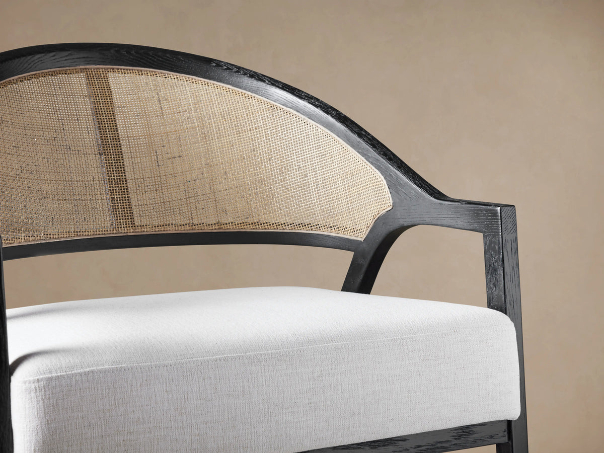 Aimee Chair in Nomad Snow, front view. Dark oak frame, curved cane rattan back, white fabric seat cushion.