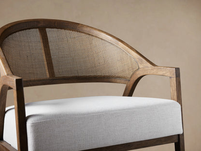 Aimee Chair: dark oak frame, arched rattan cane back, and thick white Nomad Snow upholstered seat, front view on wood floor.