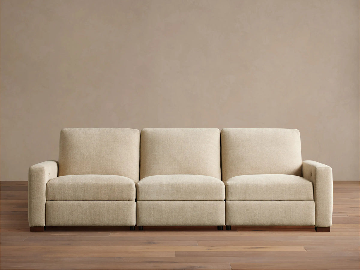 Remington Three-Piece Motion Sofa. Beige textured fabric, modular, with left arm, armless, and right arm sections, on wood floor.