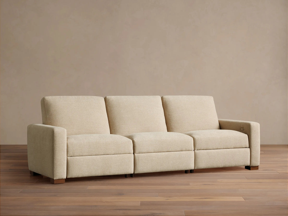 Remington Three-Piece Motion Sofa. Beige textured fabric, modular, with left arm, armless, and right arm sections, on wood floor.
