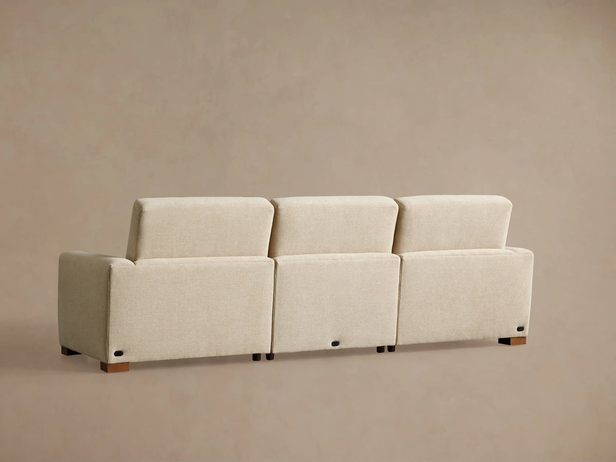 Diagonal close-up of Remington Three-Piece Motion Sofa in light beige textured fabric. Shows plush seat and back cushions from above.