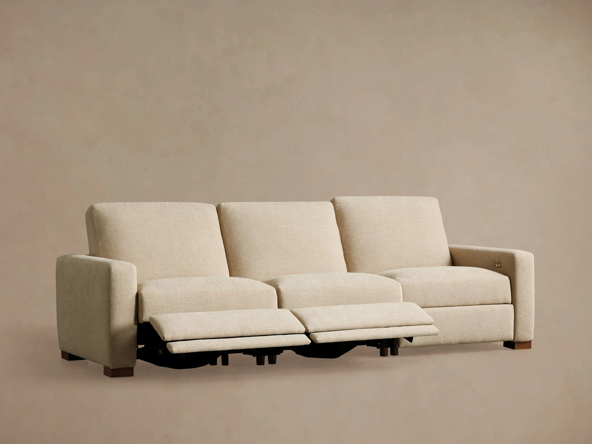 Back view of a light beige Remington Three-Piece Motion Sofa, showing its three modular sections with low backrests and wooden feet.