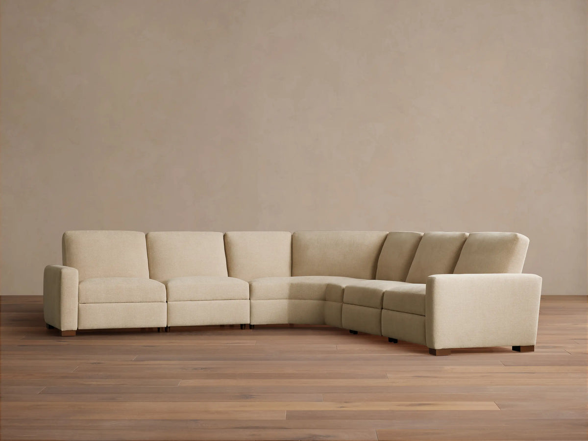 Beige Remington Five-Piece Motion Corner Sectional, one recliner extended, with decorative pillows in a modern living room.