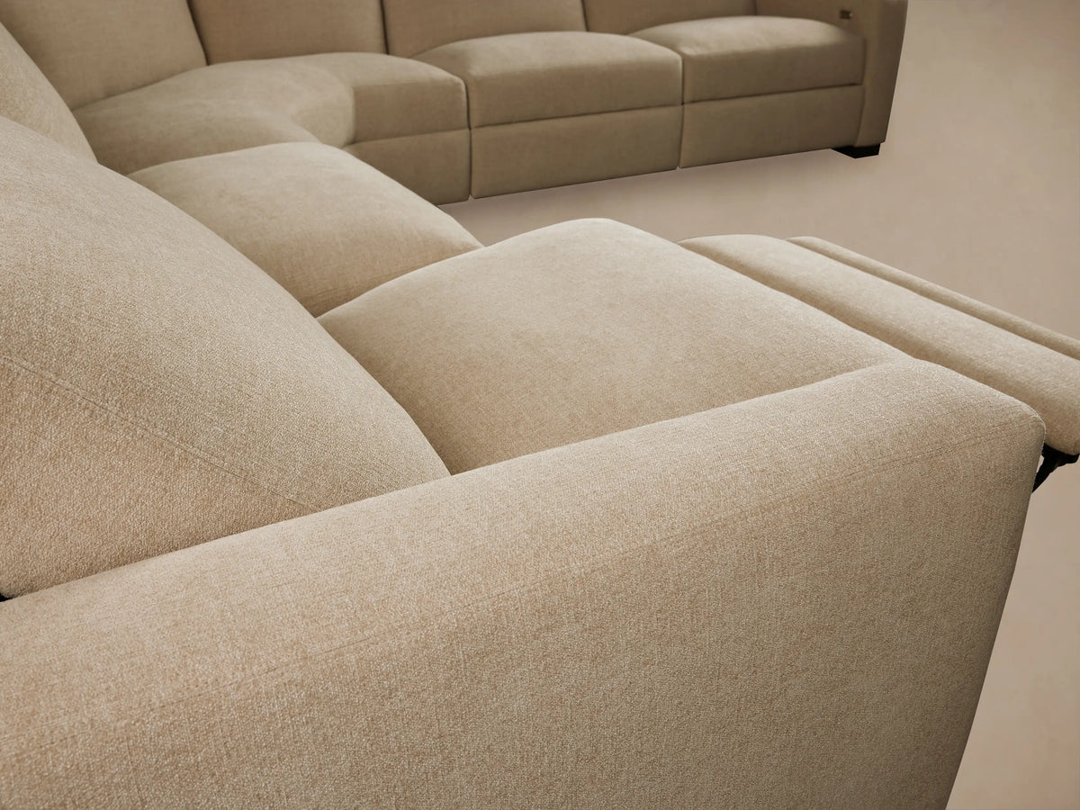 Close-up of Remington Sectional's beige textured fabric backrest, showing a modern champagne metallic recliner control.