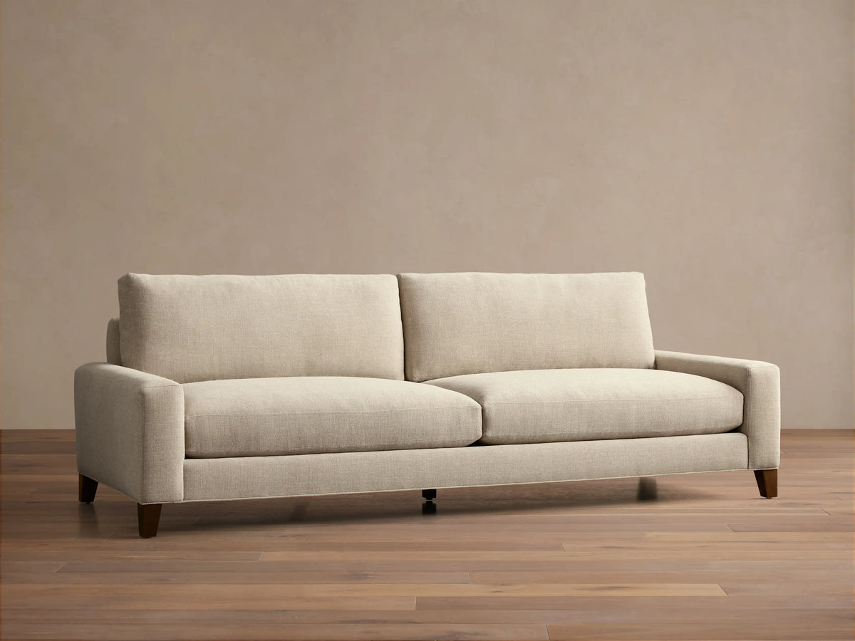 Front view of the light beige Remington Elevated Sofa with two seat cushions, two back cushions, and dark mocha-finished elevated legs.