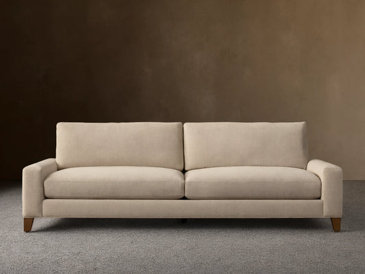 Front view of the light beige Remington Elevated Sofa with two seat cushions, two back cushions, and dark mocha-finished elevated legs.