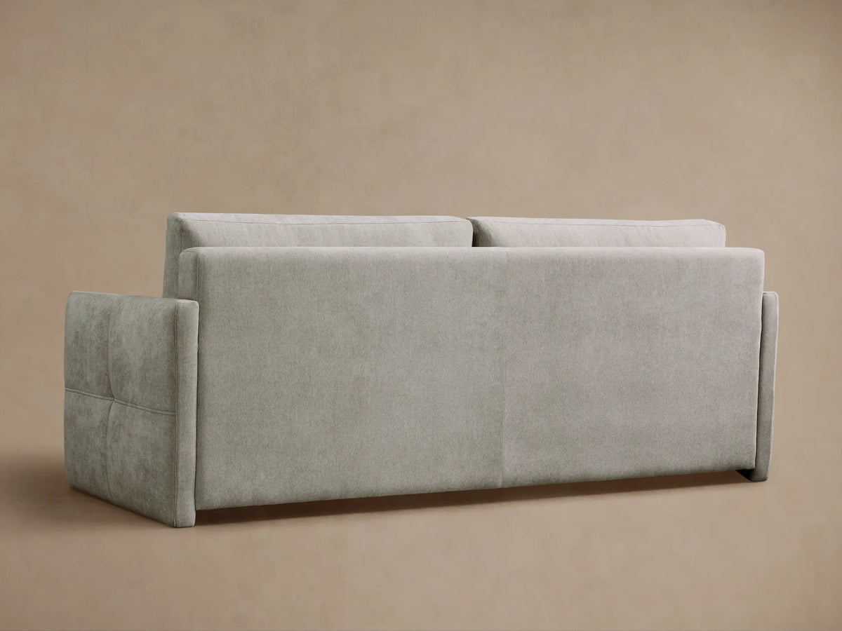 Reece Sleeper Sofa partially open, revealing its white quilted mattress and light gray fabric cushions within a dark interior.